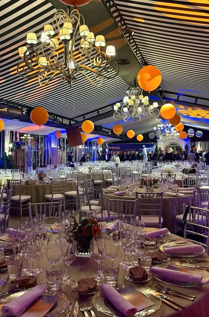 Cena de empresa en el salón · mesas vestidas, arañas y globos colgando del techo